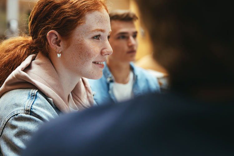 AdobeStock_429417278 / Jacob Lund eine junge roithaarige Frau lernt mit Freunden